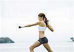 Young woman working out with weights, outdoors