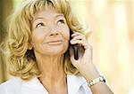 Senior woman using cell phone, looking up