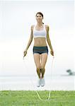 Young woman jumping rope, outdoors