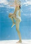 Teenage girl stretching leg underwater