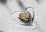 Stone on snow with heart traced around it