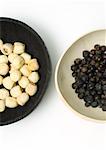 Two bowls, one containing lotus seeds, one containing dried juniper berries