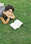 Woman lying in grass, reading