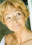 Femme Senior avec crème hydratante sous les yeux