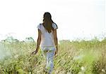 Girl walking through field, rear view