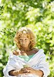 Senior woman wearing bathrobe, holding mug, outdoors