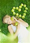 Femme couchée dans l'herbe, à côté de pommes disposées en forme de coeur