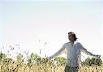 Man standing in field with arms out