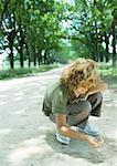 Boy crouching in dirt road