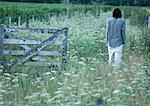 Homme qui marche dans un champ, porte de passage en bois, vue arrière