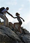 Hikers, man helping girl up rocks