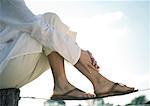 Woman sitting on wooden post resting feet on wire