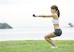 Young woman working out with weights, outdoors