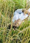 Man lying in tall grass, eyes closed