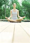 Woman sitting on deck, in lotus position