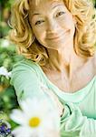 Senior woman holding out flower, portrait