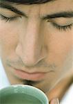 Man smelling cup of tea, eyes closed, close-up