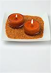 Candles on sand in square dish