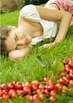 Woman lying in grass, cherries in foreground