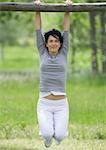 Young woman hanging on horizontal bar