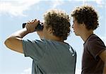 Deux jeunes hommes regardant la vue avec des jumelles, vue arrière