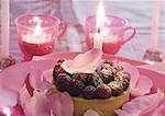 Raspberry tartlet on plate decorated with rose petals, surrounded with candles