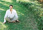 Man sitting indian style on grass, eyes closed