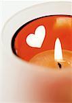 Lit candle in candleholder with heart pattern