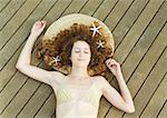 Woman lying on deck, wearing bikini, starfish in hair