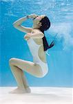 Teenage girl in pool, holding nose, underwater view
