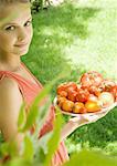Woman holding bowl full of tomatoes