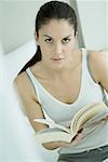 Woman holding open book, looking at camera