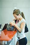 Jeune femme debout au comptoir du club santé, regardant dans le sac