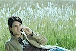 Young man reclining in field, talking on cell phone