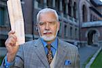 Mature businessman with a headset holding up a newspaper