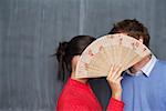 Young man and Japanese woman flirting behind a wooden fan