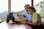Senior adult couple is sitting in a restaurant while looking at a map, selective focus