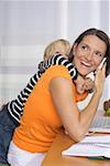 Mother phoning with a mobile phone, son (4-5 Years) embracing her form behind