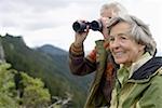 Senior adult couple with binoculars in the mountains, close-up, selective focus