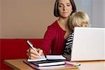 Mother taking notes while son (4- 5 Years) sitting on her lap