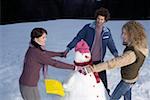 Three young people making a snowman