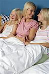Mère assis dans son lit entre ses deux filles blondes, gros plan
