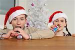 Girl and boy wearing Santa hats eating Santa Claus chocolates