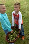 Petite fille et garçon tenant un panier avec les pommes dans les mains de vue grand angle