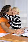 Mother taking notes while kissing her son (4-5 Years)