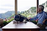 Senior adult man is sitting in a restaurant while looking through the window, selective focus