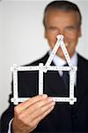 Senior businessman holding a model of a house