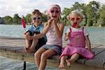Three children with sunglasses each eating an ice lolly , close- up