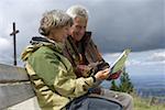 Altes Ehepaar betrachten der Karte in den Bergen