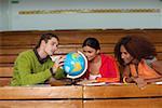 Three young people looking at a miniature-globe, selective focus